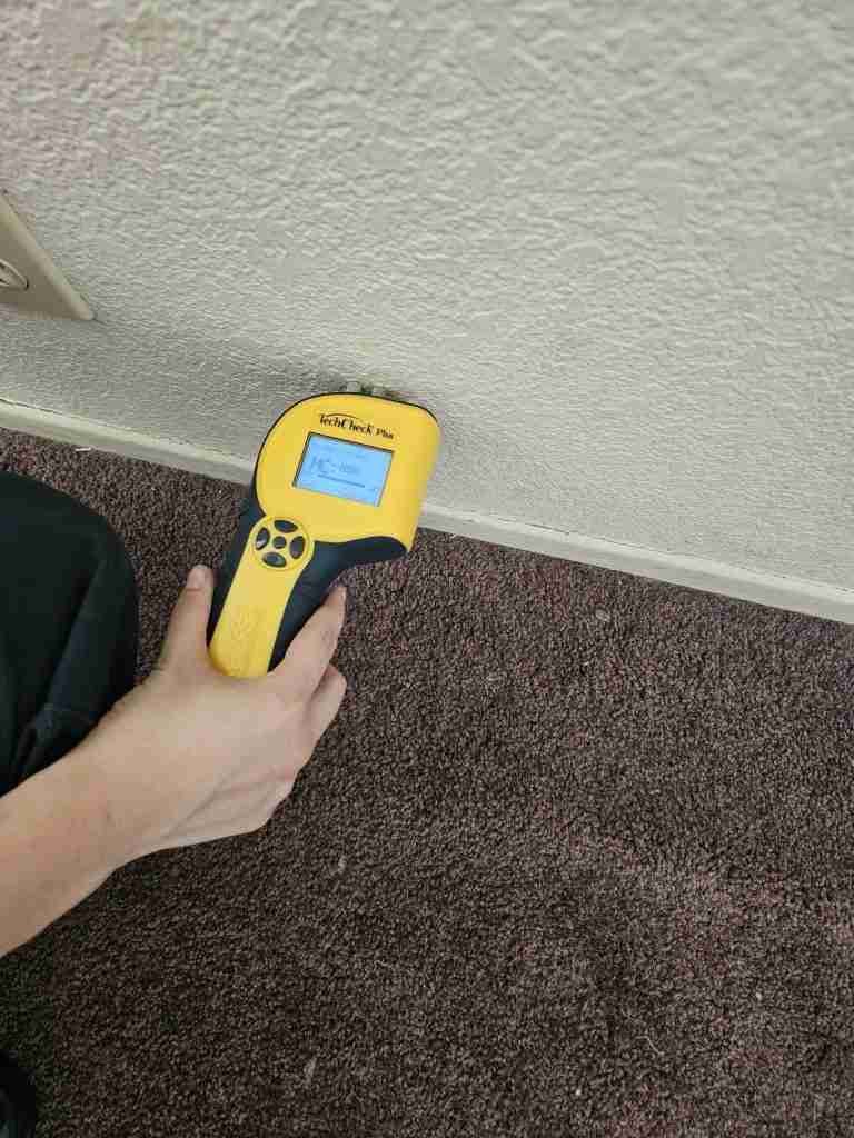 Water Damage Restoration 21 Moisture meter reading taken along a wall and carpet edge during a water damage inspection